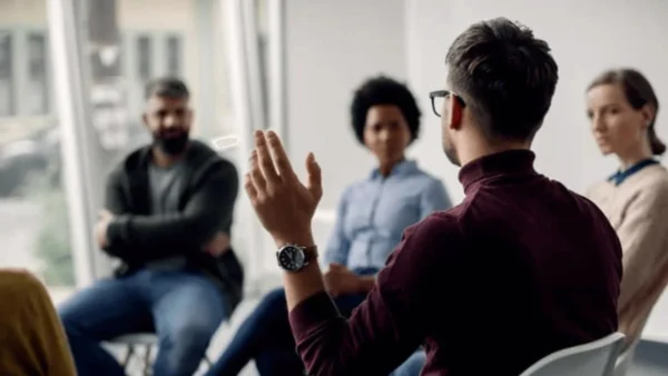 man talking with raised hand in a group circle