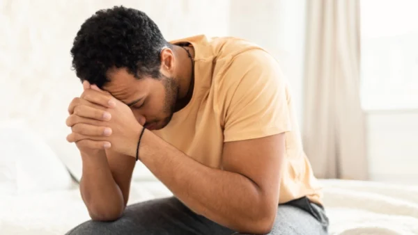 worried man looking down on the side of a bed