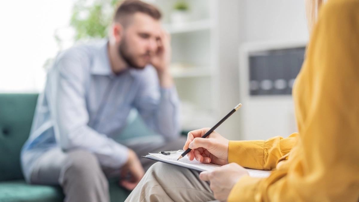 Therapist writing down notes while her client is looking distressed