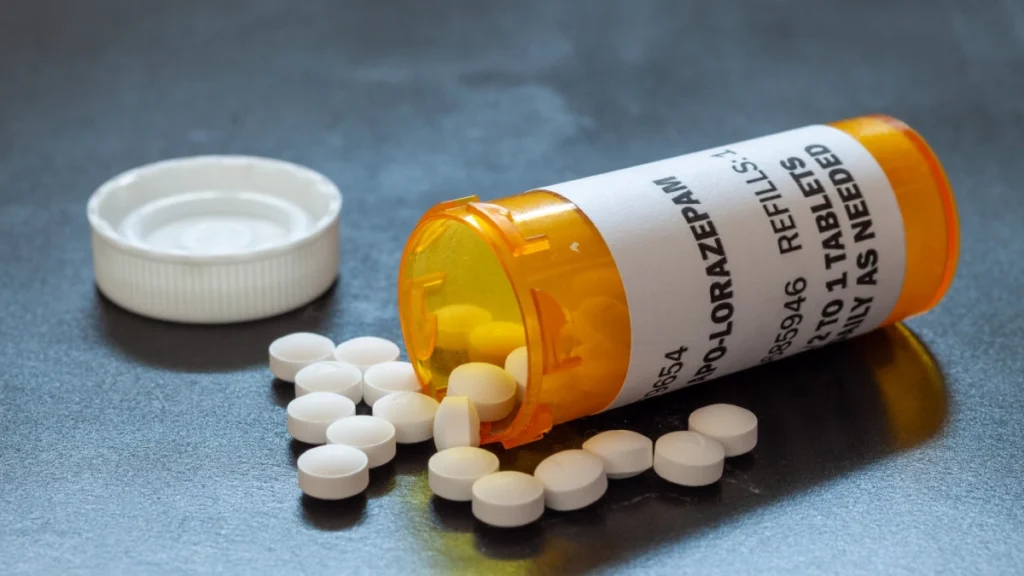 An orange prescription bottle labeled "LORAZEPAM" that has been tipped over, with white round tablets spilling out onto a flat surface.