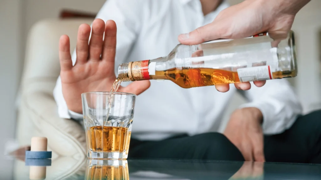 man gesturing "no" to alcohol being poured